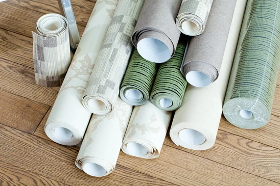 Rouleaux de papier peint d&eacute;coratif dispos&eacute;s sur parquet en bois