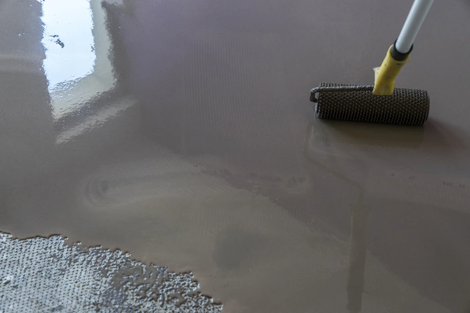 Chantier intérieur, application de revêtement de sol liquide gris sur surface plane