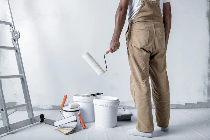 Sc&egrave;ne int&eacute;rieure sur surface blanche avec pot de peinture ouvert contenant peinture bleue m&eacute;lang&eacute;e, b&acirc;tonnet m&eacute;langeur bois ins&eacute;r&eacute;