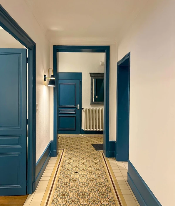 Couloir d'appartement haussmannien rénové, murs blancs, portes et plinthes laquées bleu canard