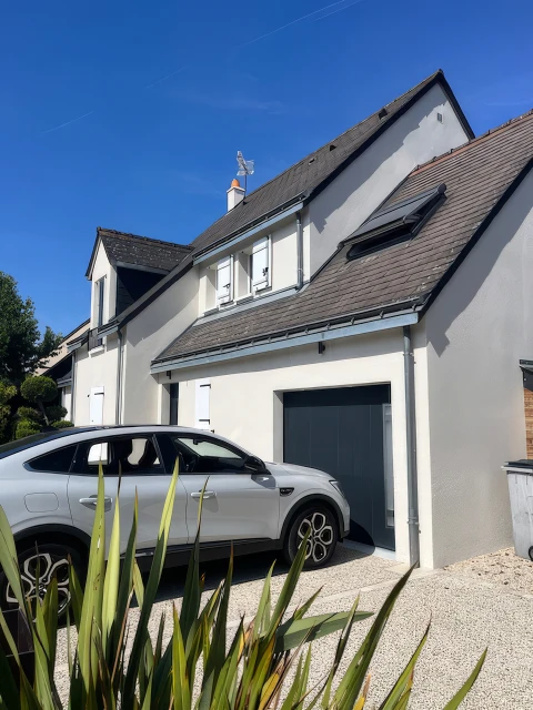 Maison individuelle pavillonnaire avec façade enduit blanc, toiture en ardoise naturelle gris anthracite, fenêtres de toit type Velux