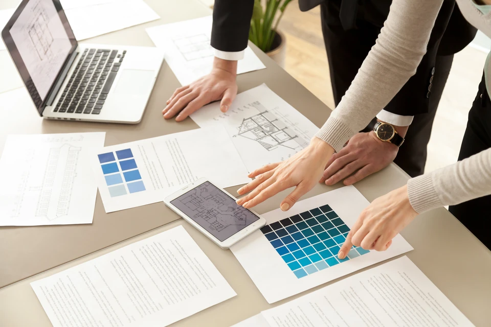 Scène d'intérieur avec trois personnes consultant des nuanciers de couleurs dans un salon moderne