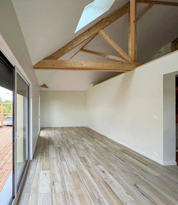 Artisan à genoux posant un parquet flottant, ajustant une lame de stratifié effet chêne doré
