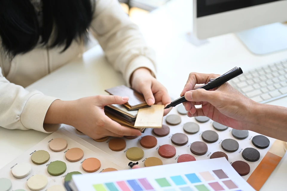 Sc&egrave;ne d'int&eacute;rieur avec une femme consultant des nuanciers de couleurs sur une table