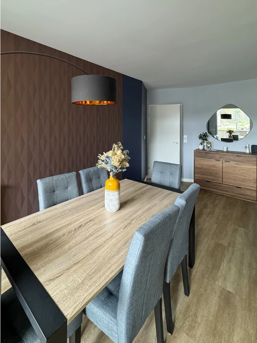 Chambre moderne aux tons bleu marine et taupe, décorée de deux chapeaux de paille posés sur des feuilles de palmier séchées fixées au mur, créant un effet soleil bohème